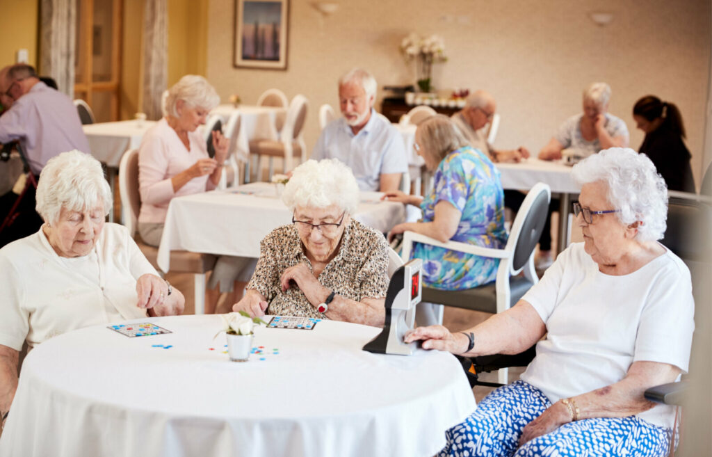 Group of seniors playing Bingo game in a common area inside an assisted living facility.