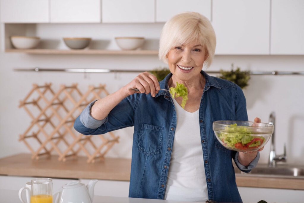 Senior woman eating green salad.