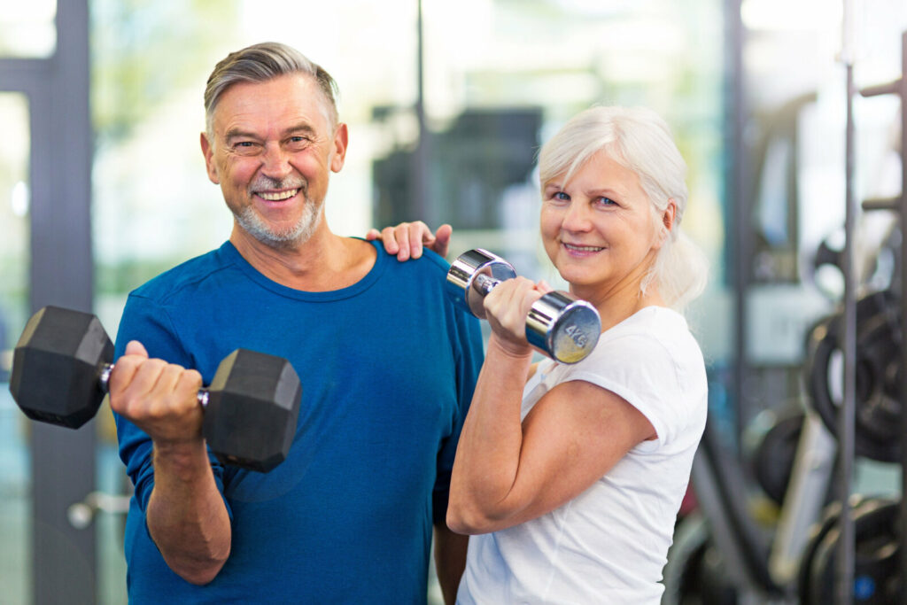 Senior couple doing strength training in a gym.