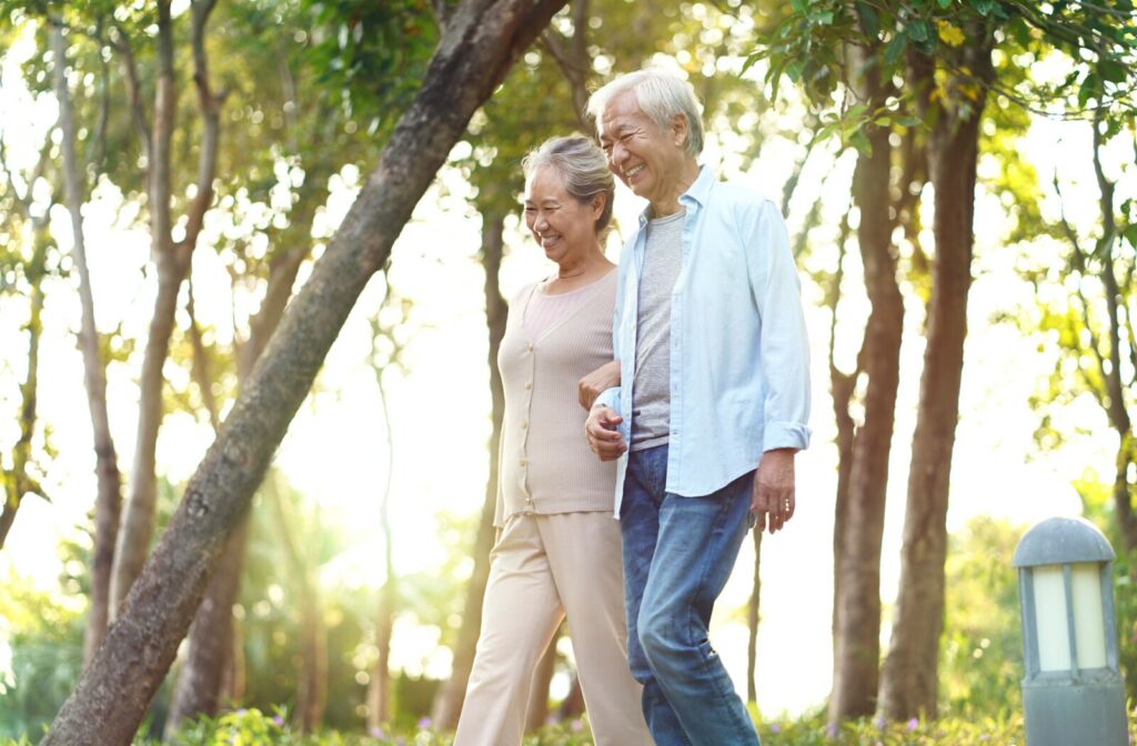 A senior couple walking in the park during sunrise.