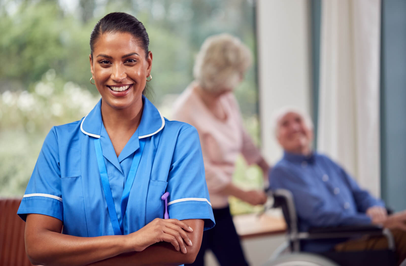 A female caregiver smiling with two seniors behind her.