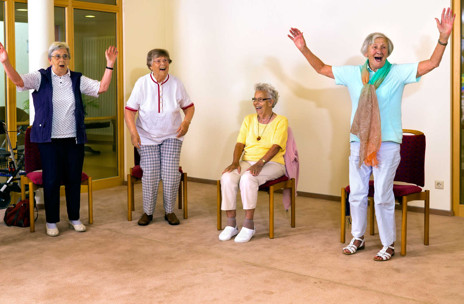 A group of senior women smiling and exercising together in a senior living community.
