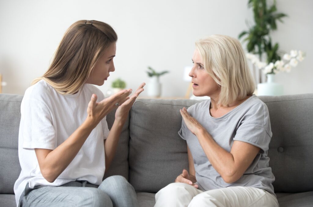 An adult child having a discussion with a parent about their negative behavior.