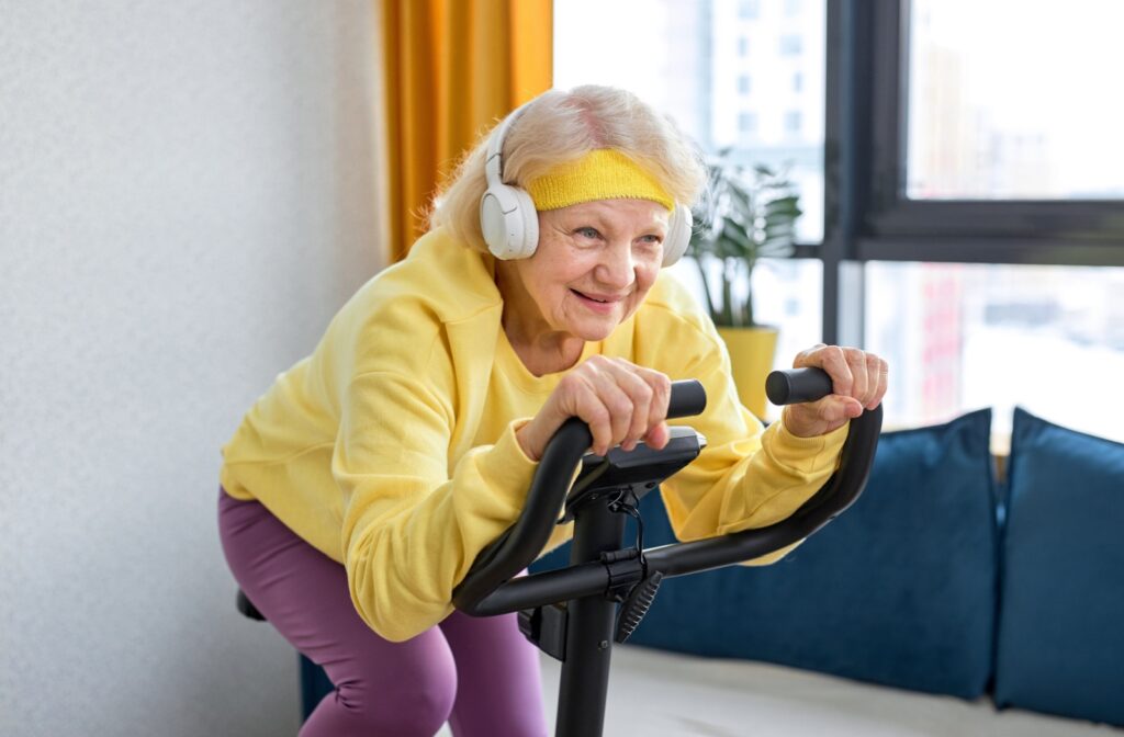 An older adult on an indoor exercise bike, wearing headphones and exercising to improve cardio health.