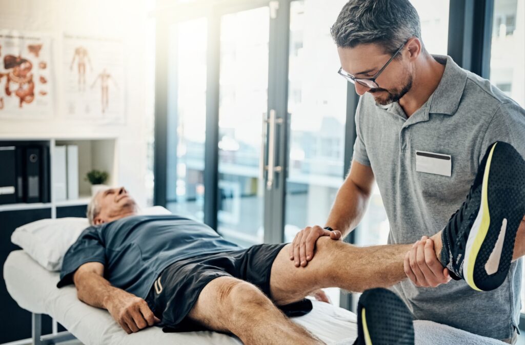 An older person has their knee examined by a physical therapist.
