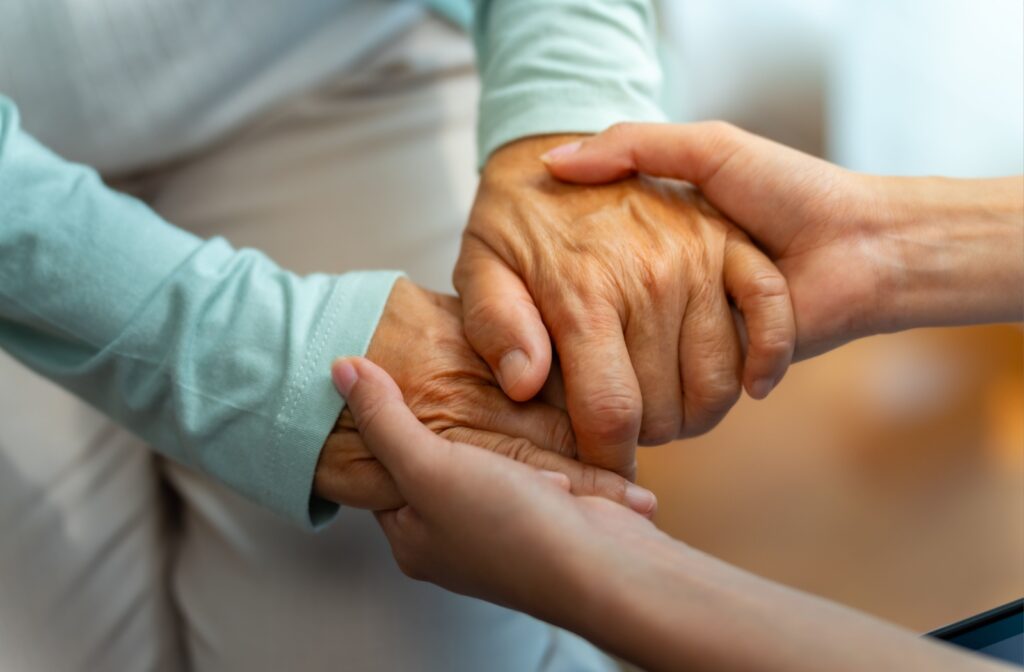 Close-up of two people holding hands in a comforting gesture.