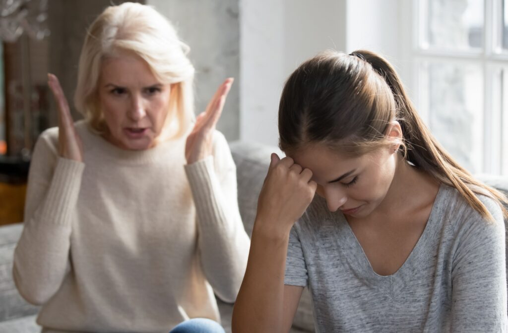 A frustrated adult leans their head on their hand while listening to their older parent refuse to consider assisted living