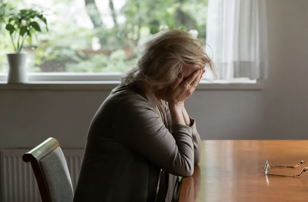A frustrated senior sits at a table after getting into an argument with their child.