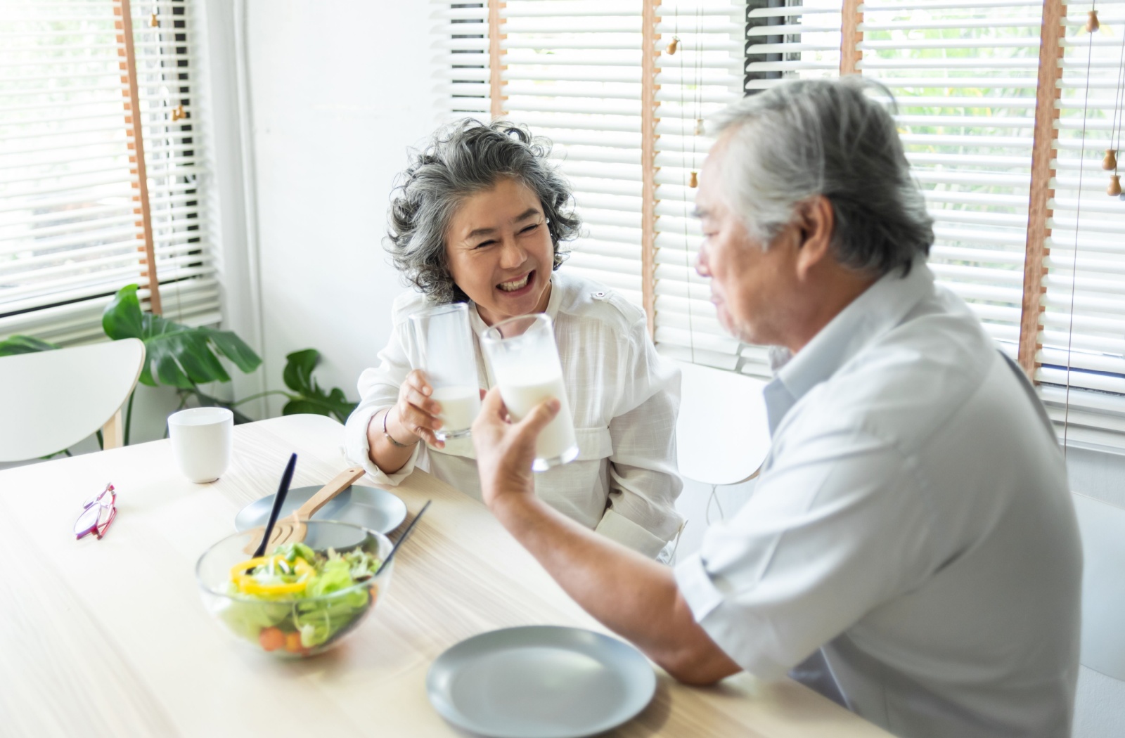 A happy older adult couple drinking milk together.