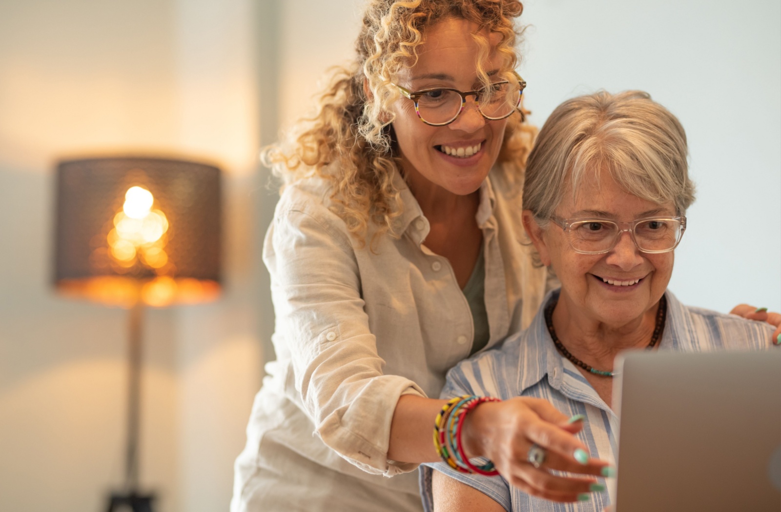 An adult child helping their parent explore assisted living communities on a laptop.