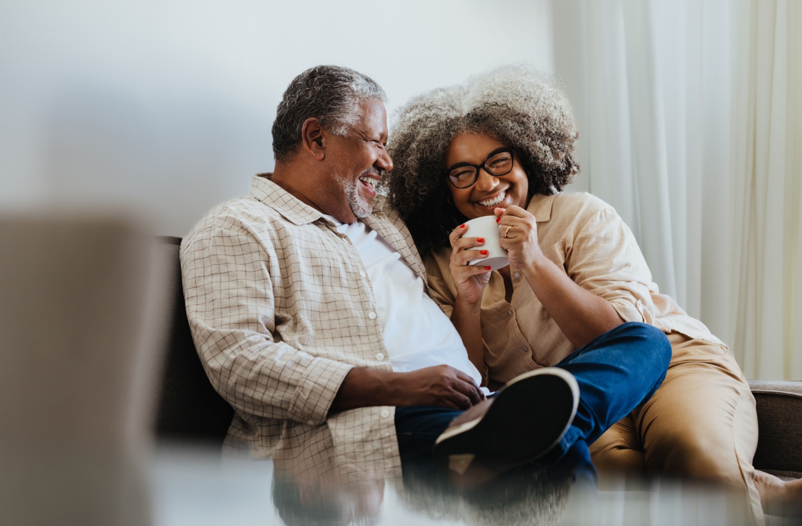 Senior couple laughing together while spending time on the couch.