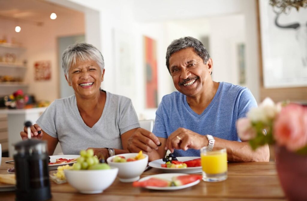 Two seniors in assisted living share each other’s company over a healthy breakfast full of nutritious and delicious fruits
