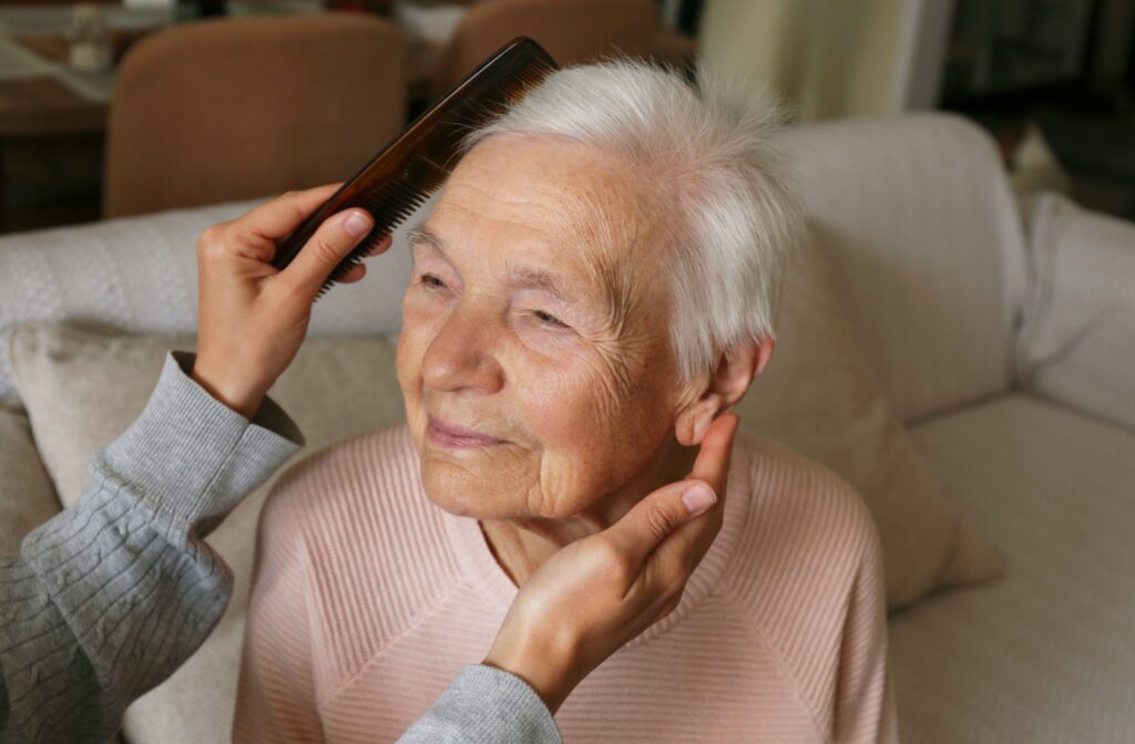 A senior gets their hair combed in assisted living.